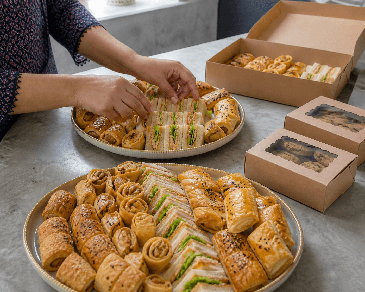 Hands arranging sandwiches and savoury pastries for a large bakery order